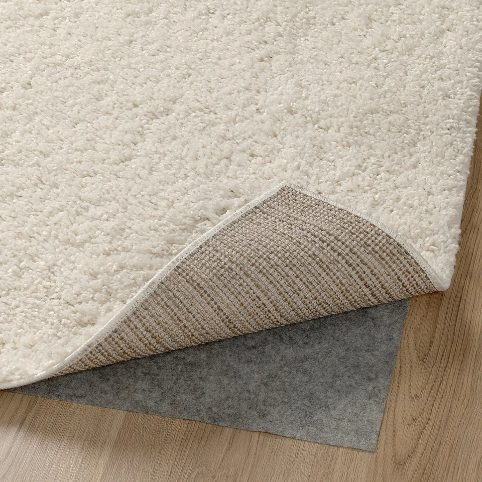 Thick, plush rug with dense pile for warmth and comfort, padding visible underneath, on wooden floor.