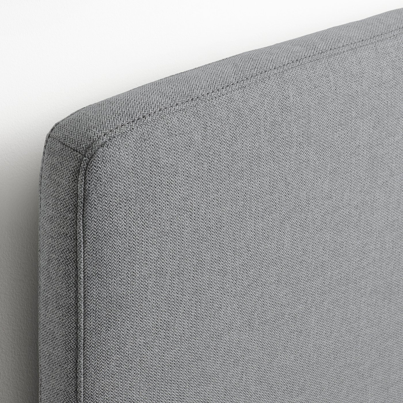 Close-up of a neatly upholstered bed frame corner, showcasing premium fabric and precise stitching.