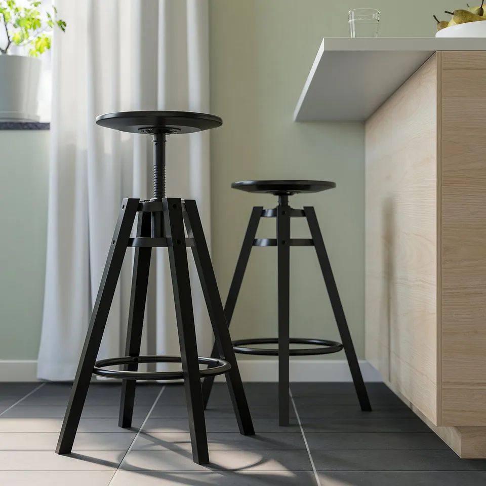 Two adjustable bar stools with round seats and black metal frames next to a wooden bar.