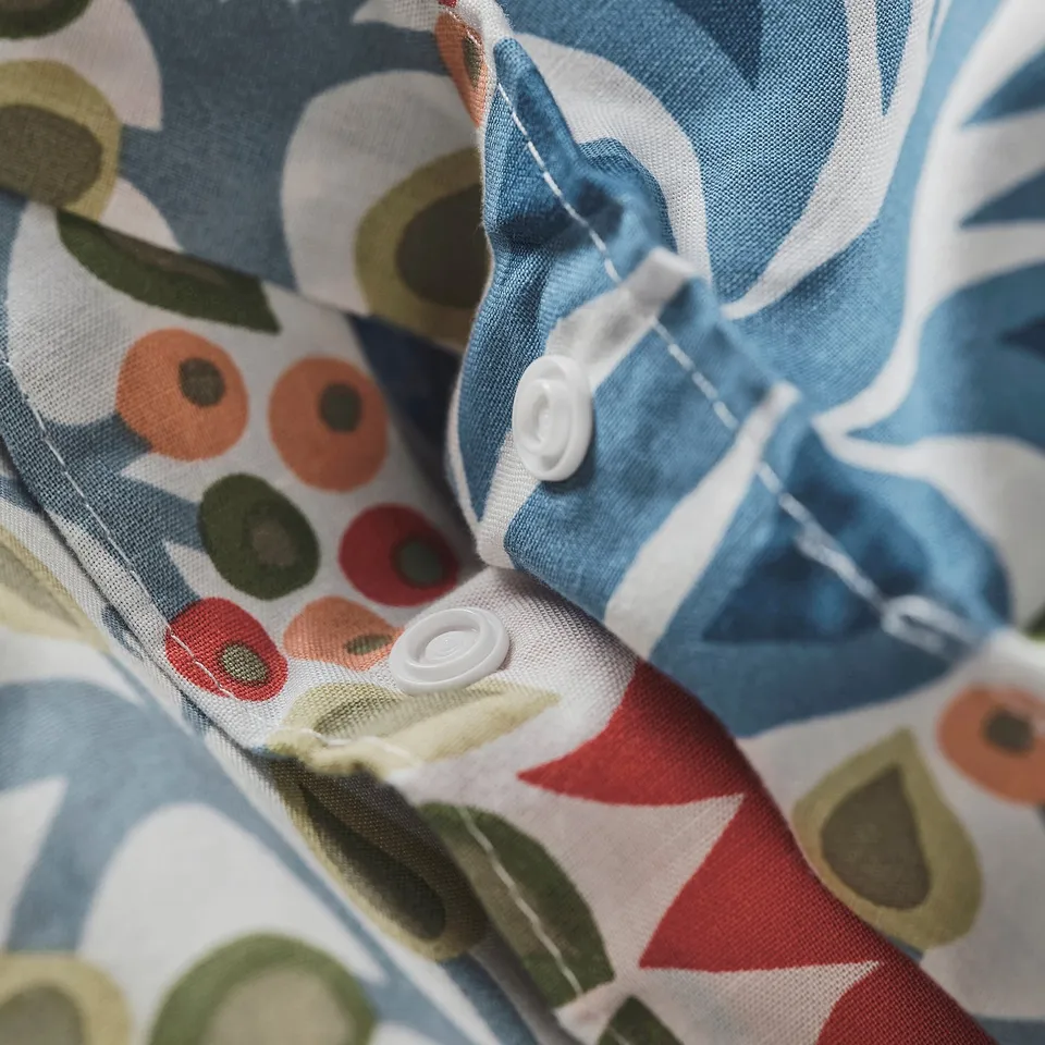 Close-up of SÄTERVIDE duvet cover with concealed press studs, showcasing intricate folklore design for easy fastening.