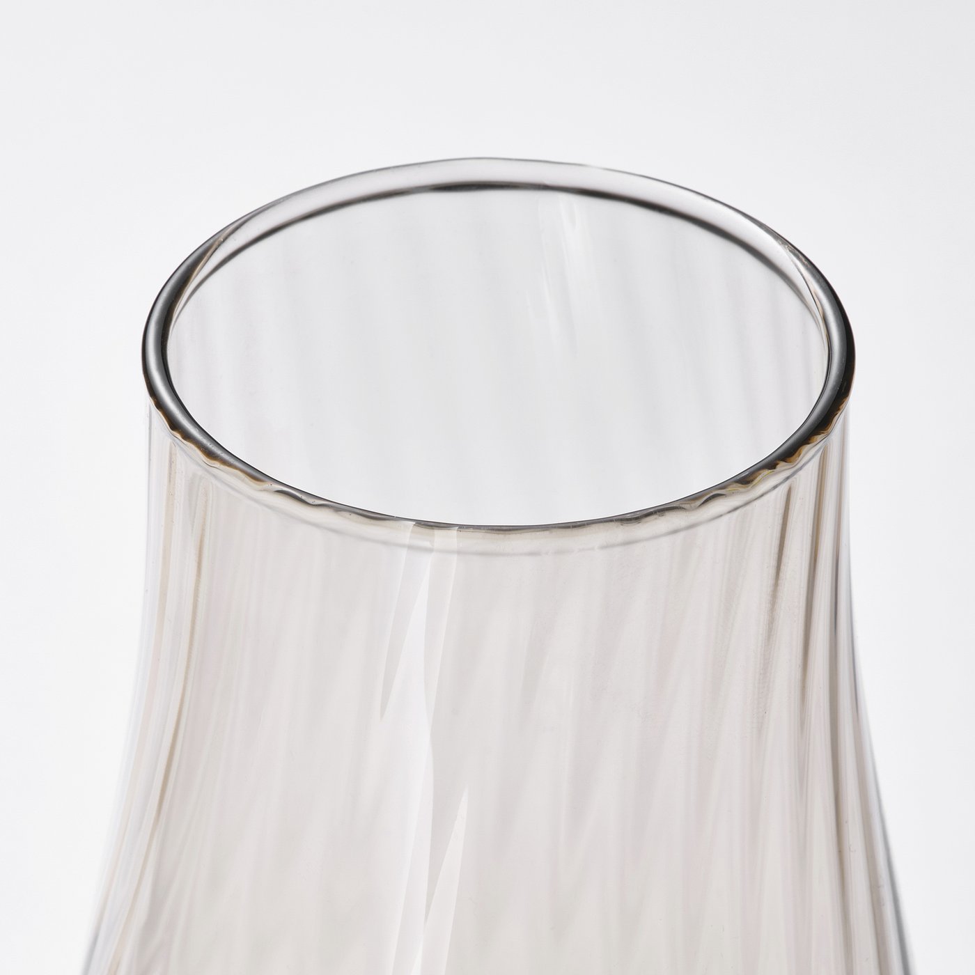 Elegant, clear glass vase with rippled texture, catching soft light.