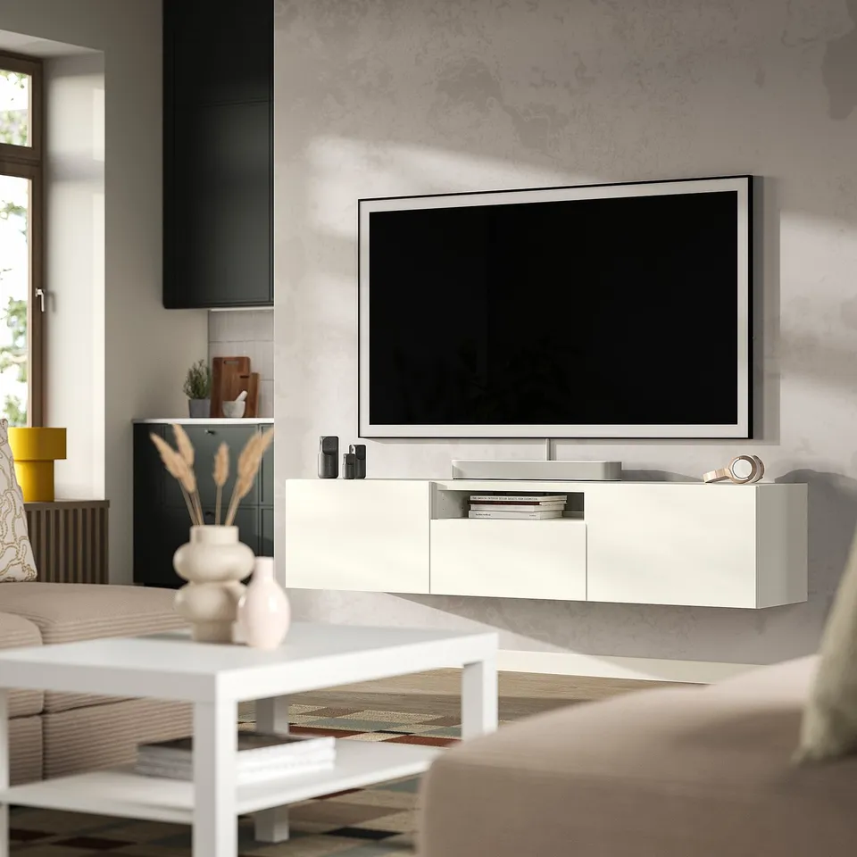 Modern living room with BESTÅ white tv stand, large flat screen, decor, coffee table, and couch. Clean, minimalist design.