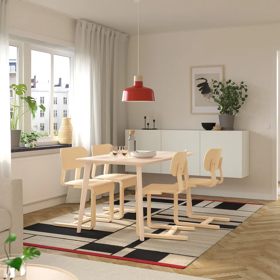 Modern dining area with LISABO light wood table and chairs, red pendant lamp, white cabinet, striped rug, and large window.