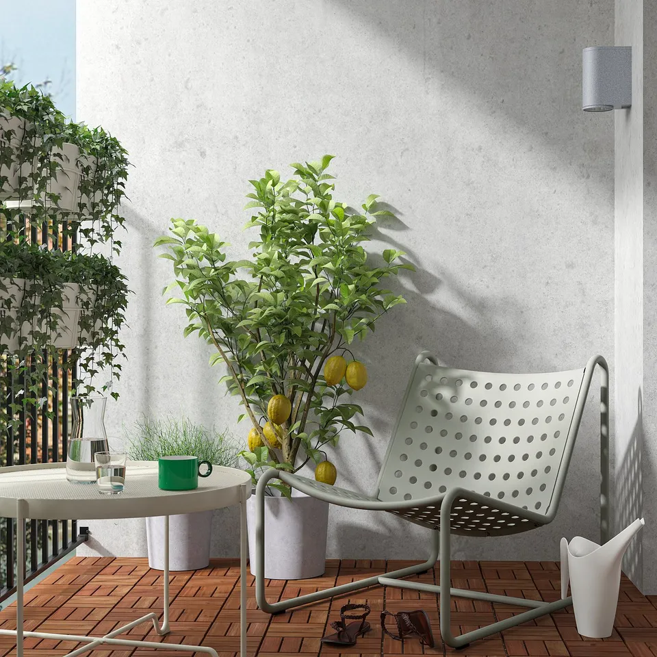Modern balcony with white SKOGSÖN chair, lemon tree, and table. Ages with grace, durable metal construction. Perfectly sized for small spaces.