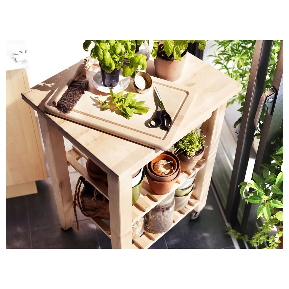Small wooden trolley with wheels, holding potted plants and cutlery. Rustic design, birch material.
