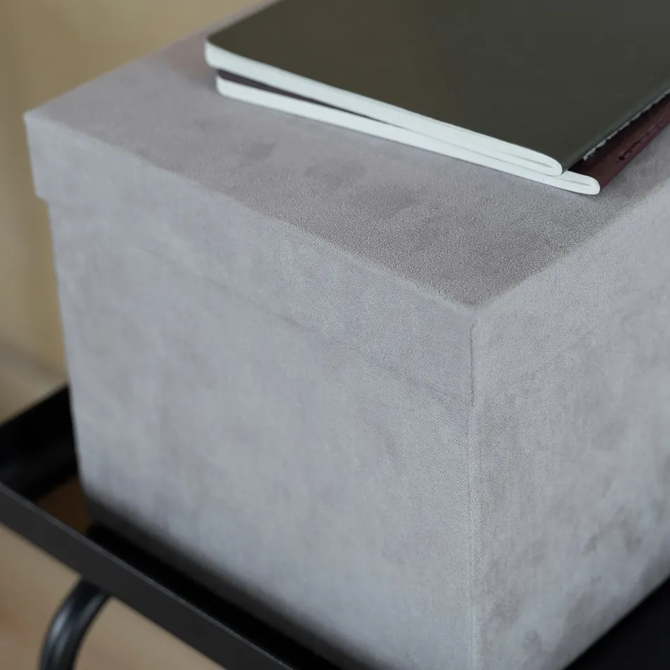 Grey velvet storage box on metal shelf, great for organising small items.