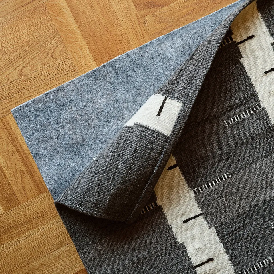 Grey handwoven rug with birch pattern, reversible sides, ideal for living room or under dining table.