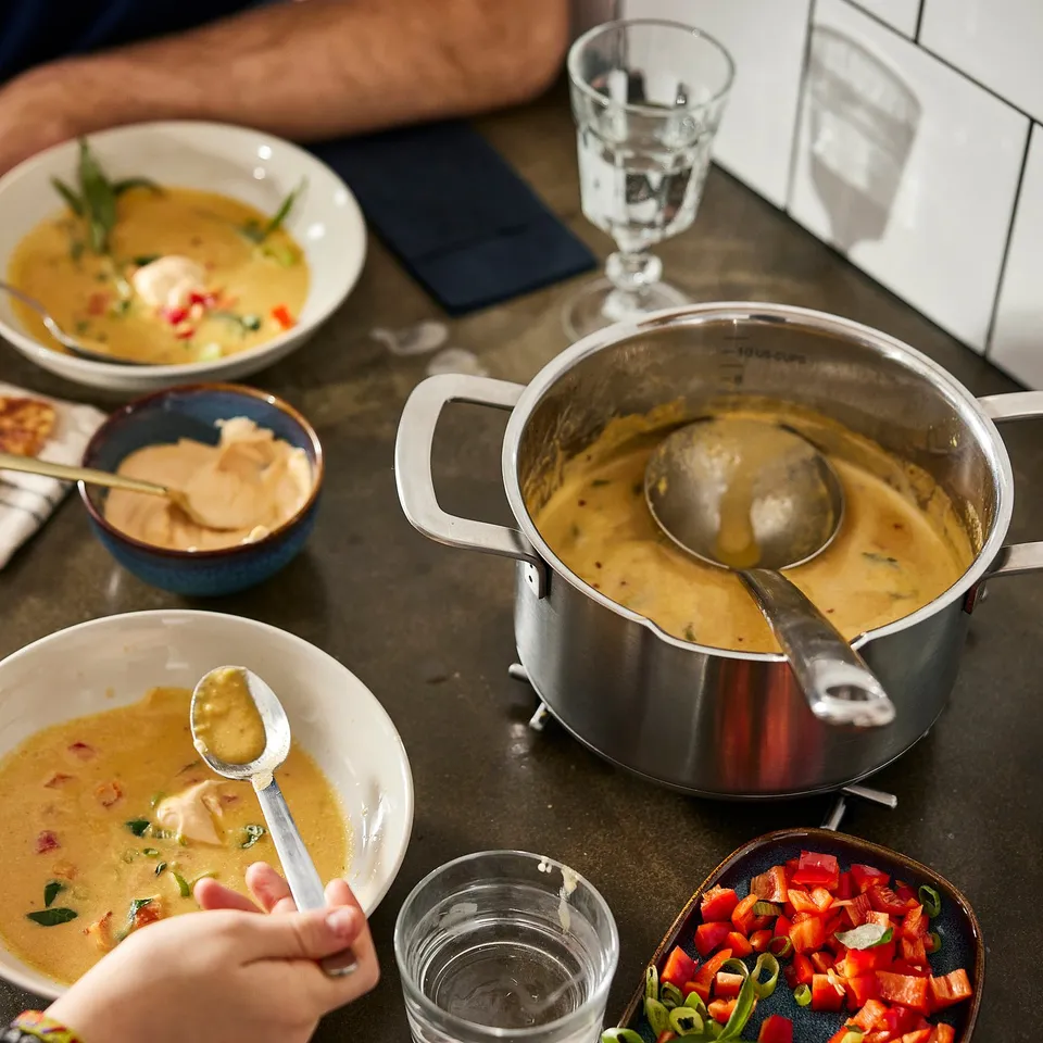 Kitchen: soup on stove, ladle, bowls, sauces, veggies.