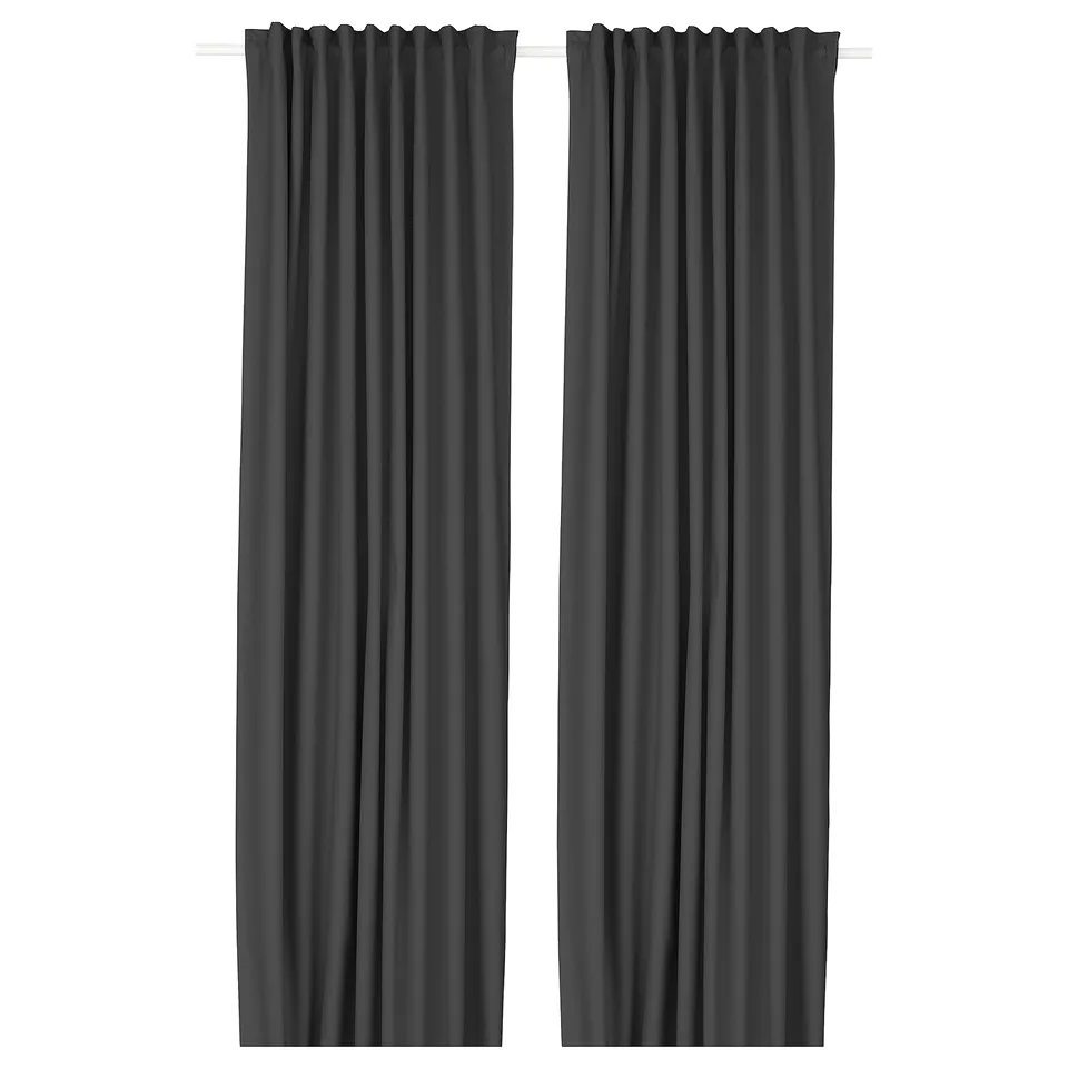 Two dark grey KORGMOTT block-out curtains with elegant, textured fabric and eyelet design hang side by side, creating neat folds.