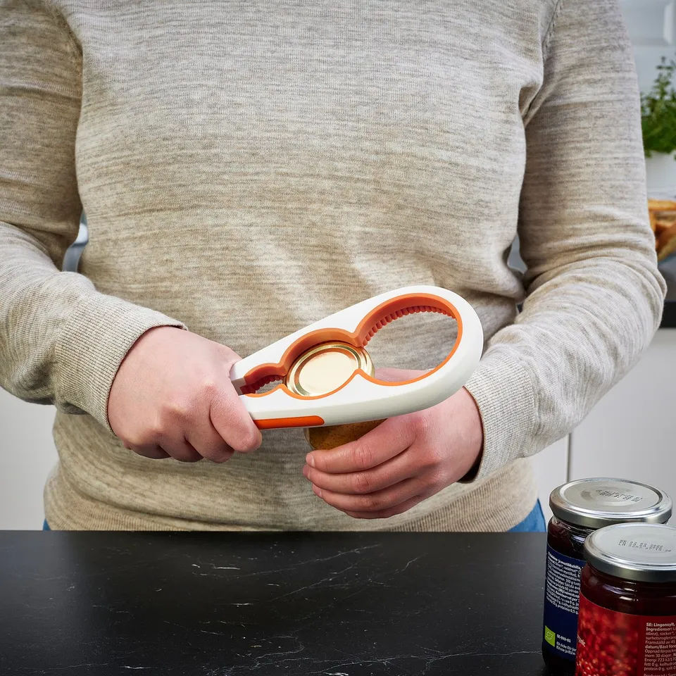 Person uses UPPFYLLD jar opener to twist off a tight jar lid, demonstrating its grip and function in the kitchen.