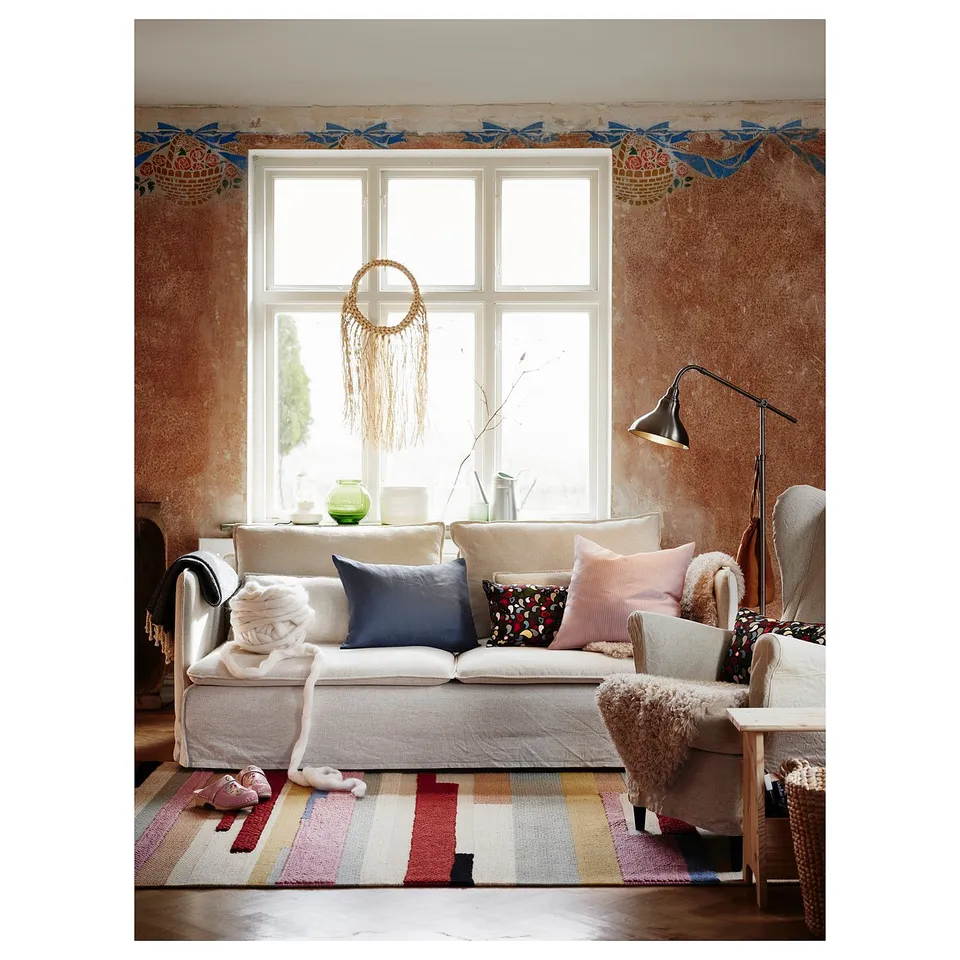 Vintage living room with white sofa, colourful pillows, striped rug, and macrame decor.