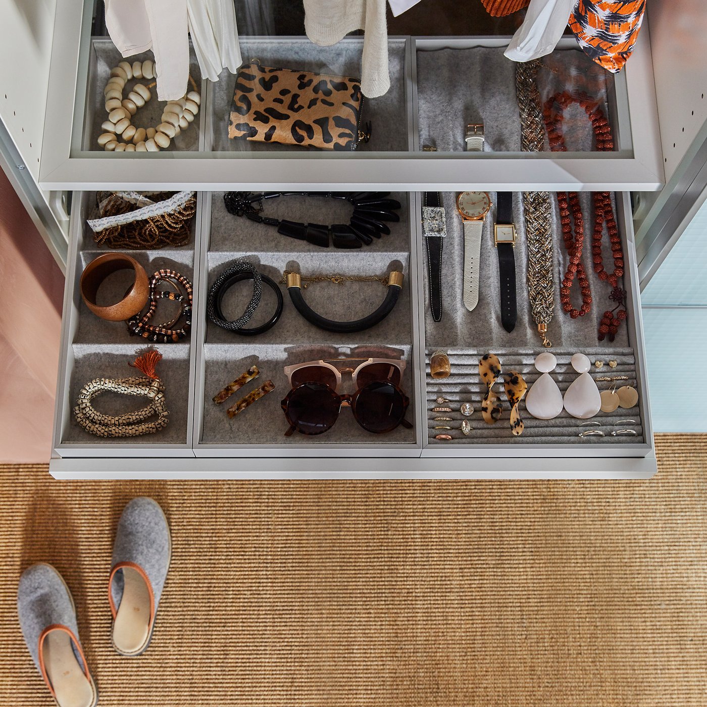 KOMPLEMENT jewellery organiser with felt lining, various compartments for accessories, placed on beige carpet.