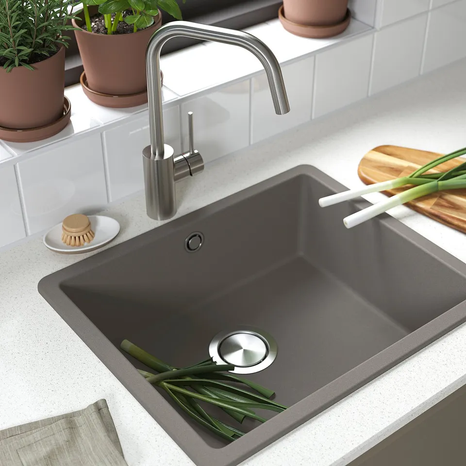 Modern kitchen sink with stainless tap, dark countertop, and herbs. Stain and heat resistant, includes drain cover.