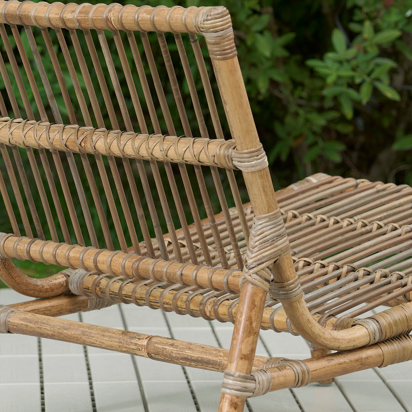 Wicker outdoor furniture on a tiled surface. Close-up shows intricate weaving and natural material texture.