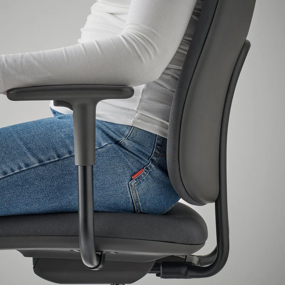A person sits in an office chair, leaning back, showing the height-adjustable seat and armrests in use.
