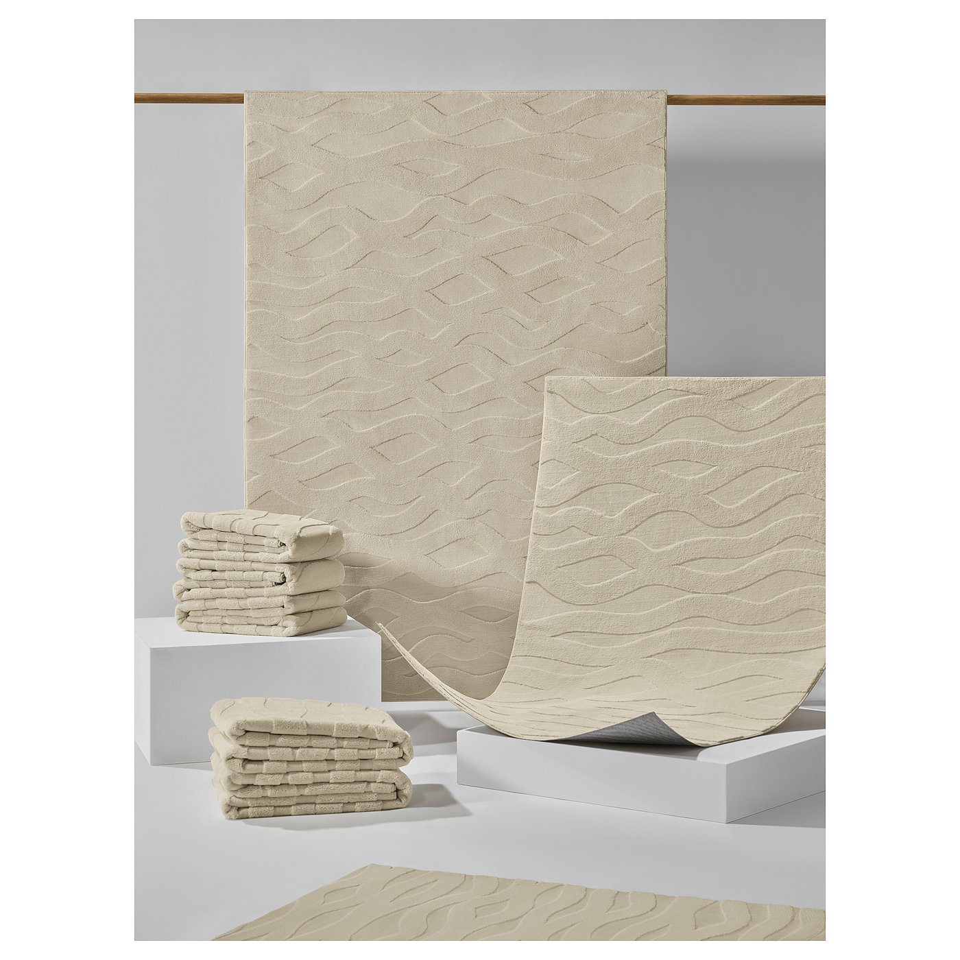 VÄXELFEL rugs in beige. They feature a plush, textured wavy pattern and a non-slip back.