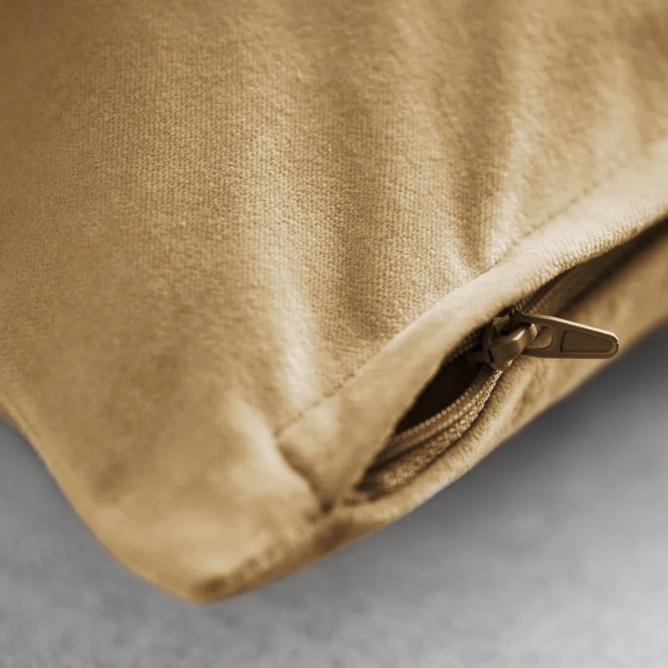 Close-up of plush, gold cushion cover zip, showcasing soft cotton velvet texture.