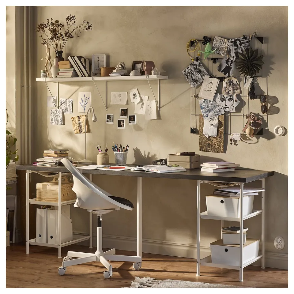 Modern office desk setup: LAGKAPTEN. White desk with shelves, chair, books, notes, art on wall. Organised workspace with decor.