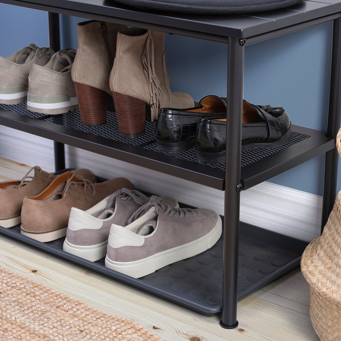 Black metal shoe rack with three shelves holding various pairs of shoes.