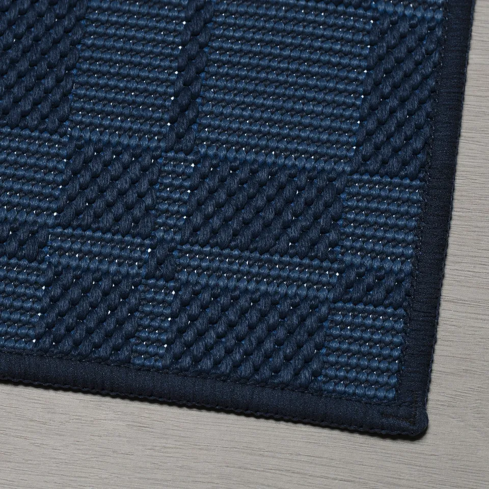 Dark blue textured rug with intricate patterns, placed on a wooden floor.
