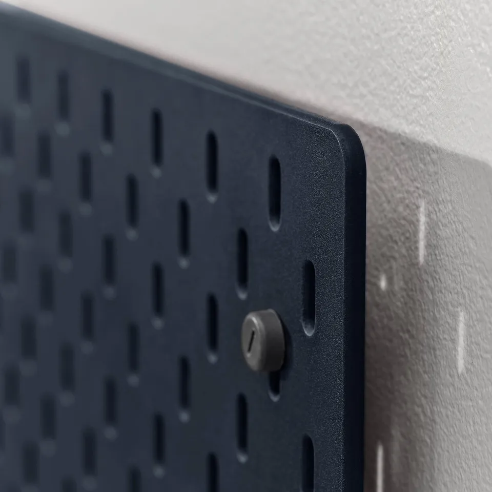 Black pegboard mounted on a light-colored wall, showing one of its pegs.