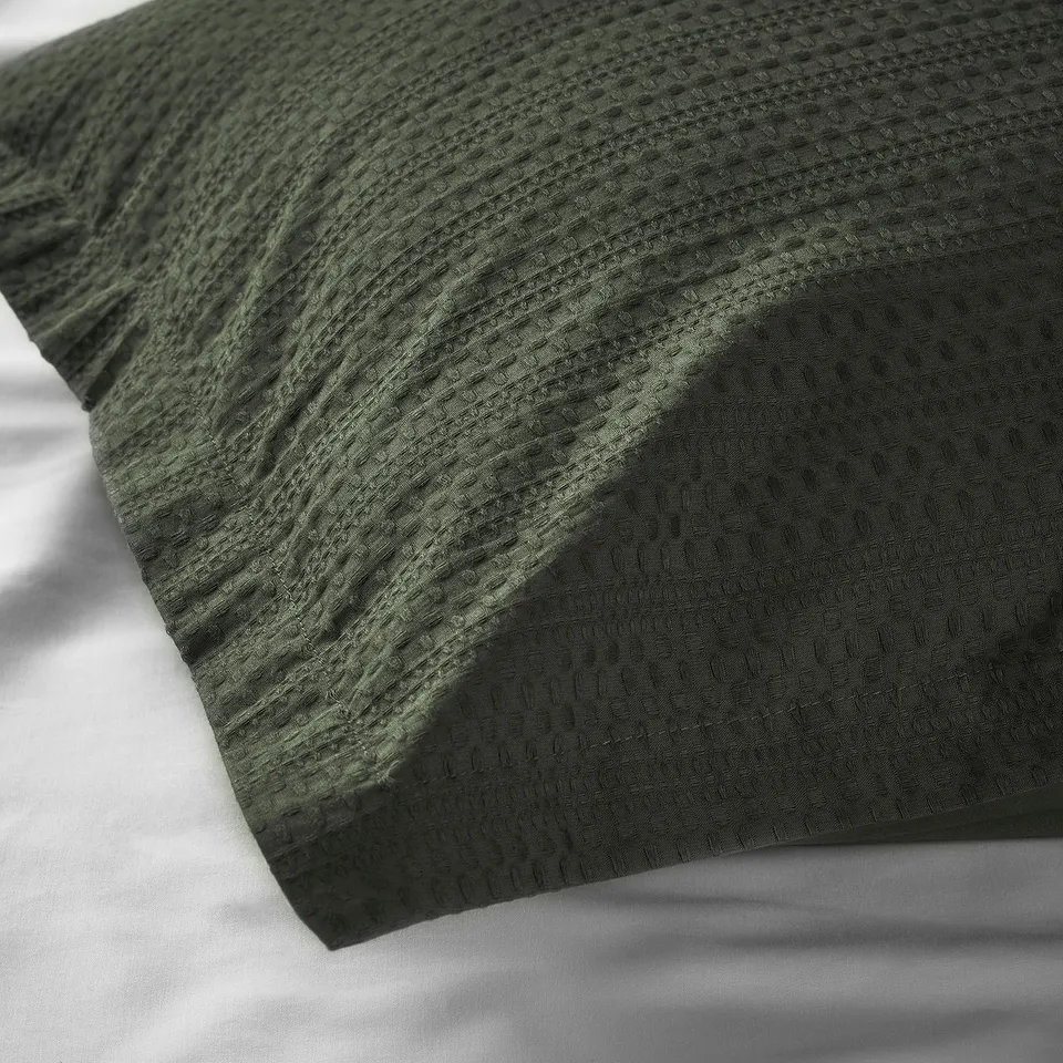 Dark green waffle weave duvet cover, folded neatly, showcasing soft cotton texture.