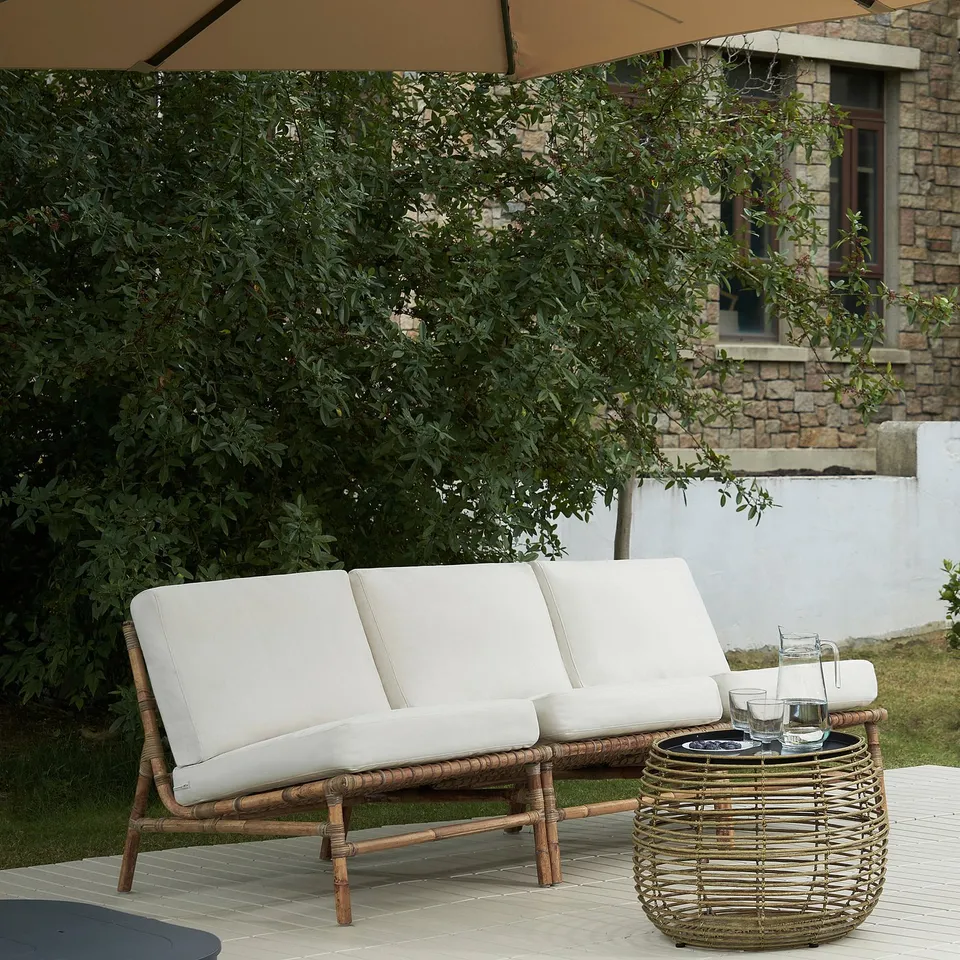 TVARÖ wicker outdoor sofa with white cushions, patio with coffee table, drinks.