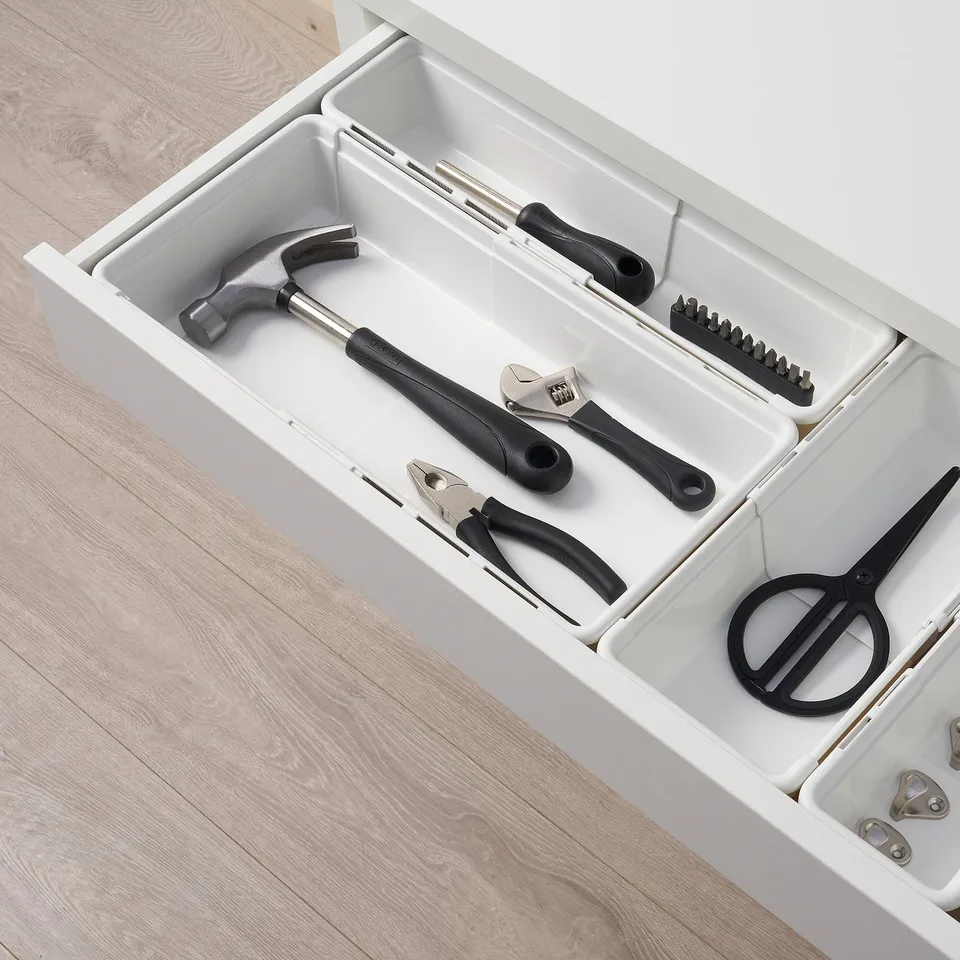 White organiser box holding tools: hammer, wrenches, pliers, scissors. Ideal for various sizes and spare parts.