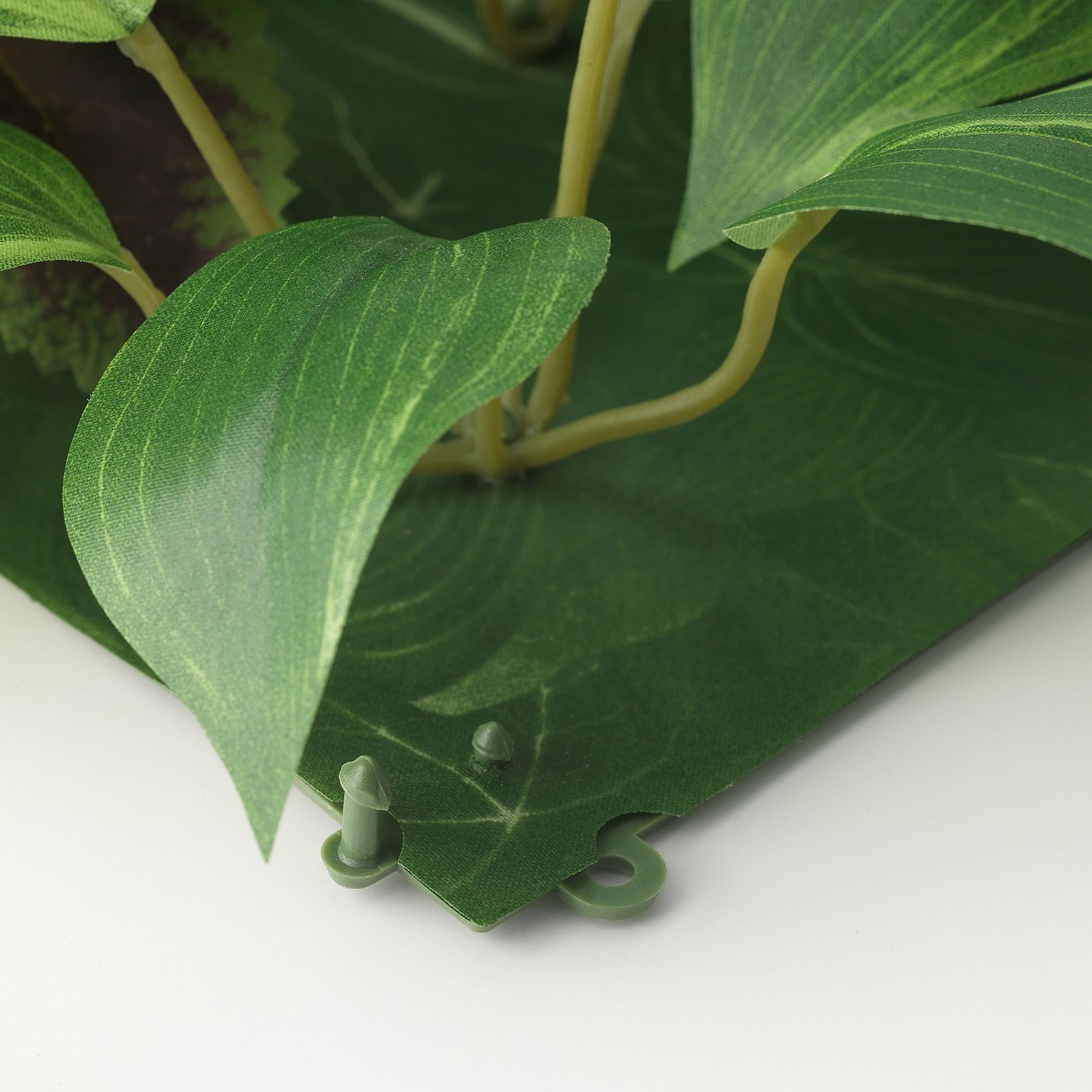 Artificial plant wall panel, made with recycled plastic, showcasing green leaves and a sturdy base.