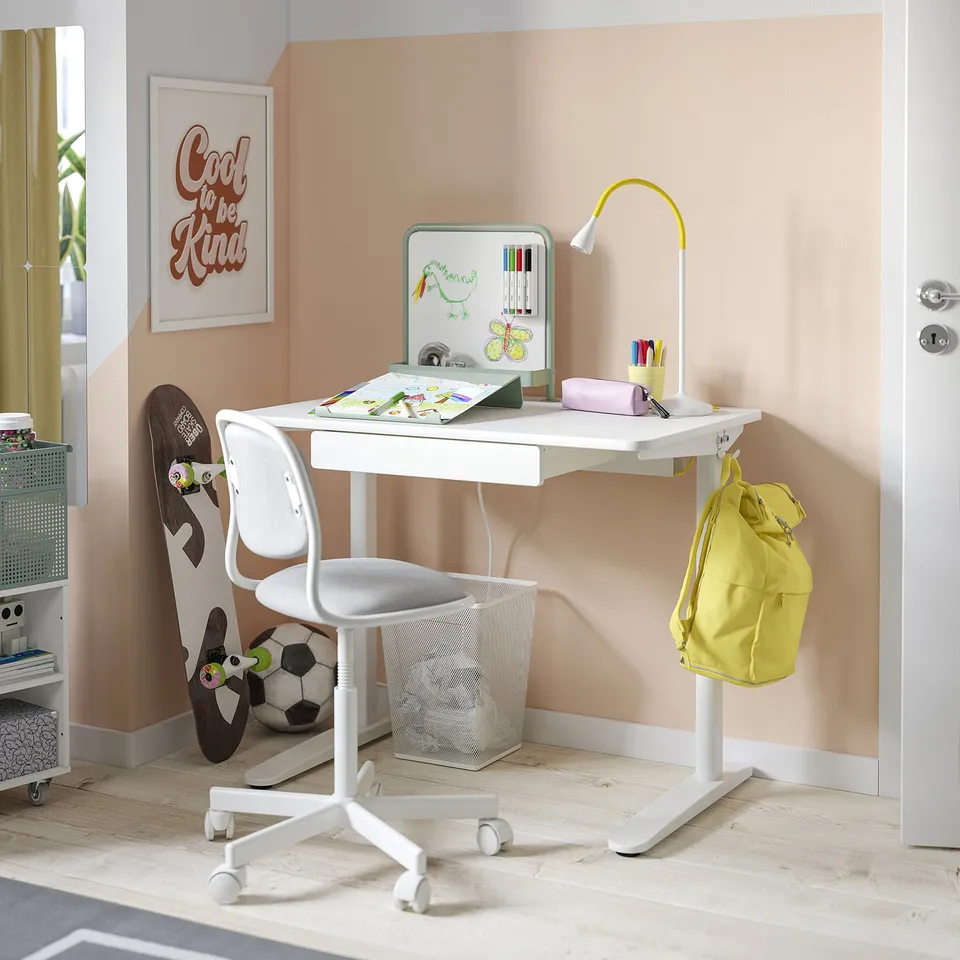 Childs white study desk with magnet board, adjustable chair, yellow backpack, sports accessories, and motivational poster.