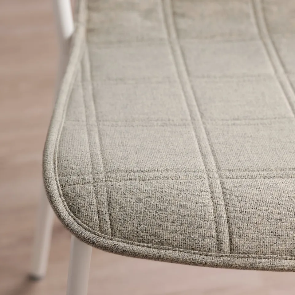 Close-up of upholstered chair cushion with fine stitching, showing quality texture and design.