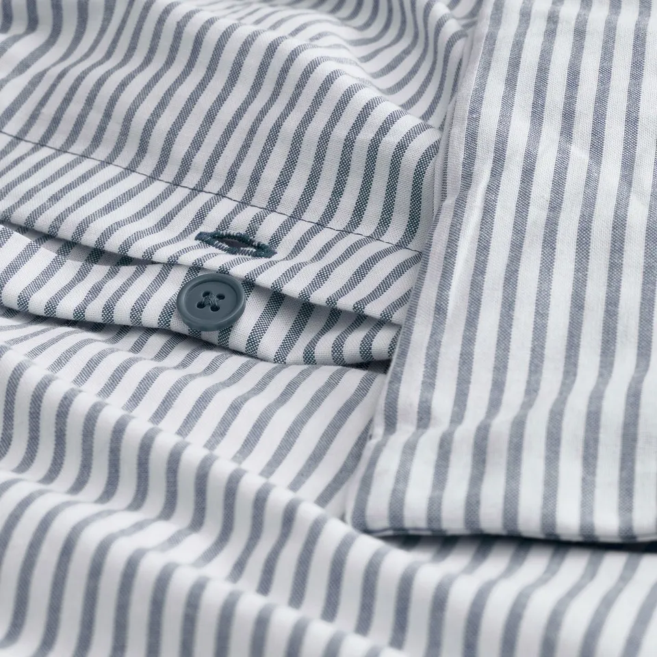 Close-up of striped SOLFIBBLA shirt with a button. Thin grey stripes, tightly woven fabric, single grey button shown.