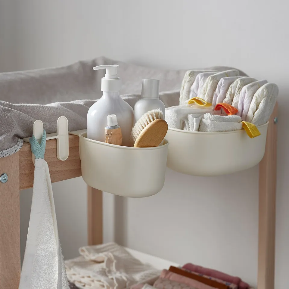 Bathroom storage baskets hang on table edge for convenient baby care.