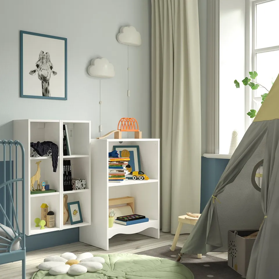 Kids room with white changing table, blue shelves, giraffe poster, toys, green accents, and cosy bed.
