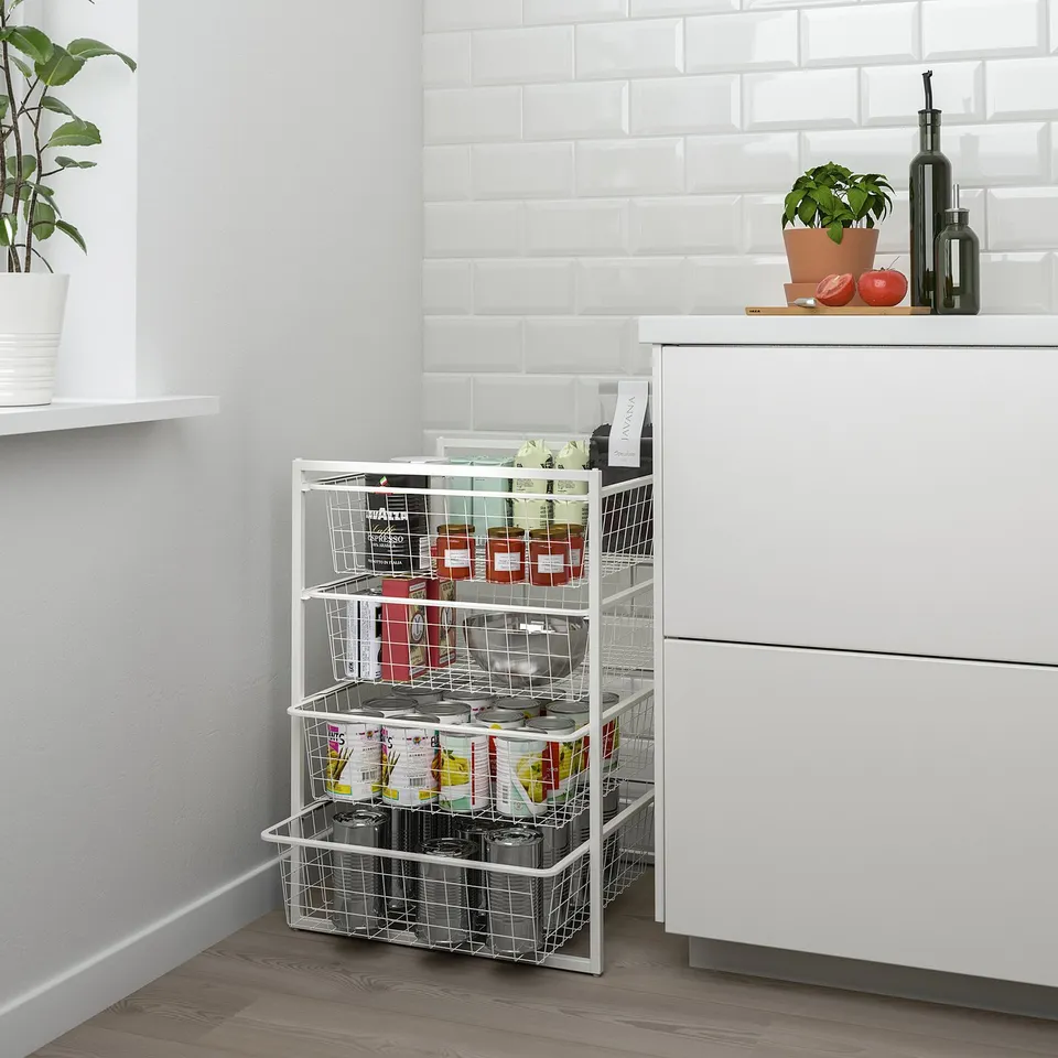 Modern white wire storage baskets filled with colourful items, contrasting with white kitchen cabinets and wooden floor.