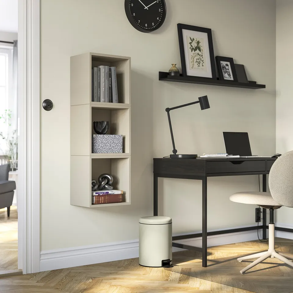Modern office setup with pedal bin, bookshelf, desk, laptop, lamp, and grey chair.