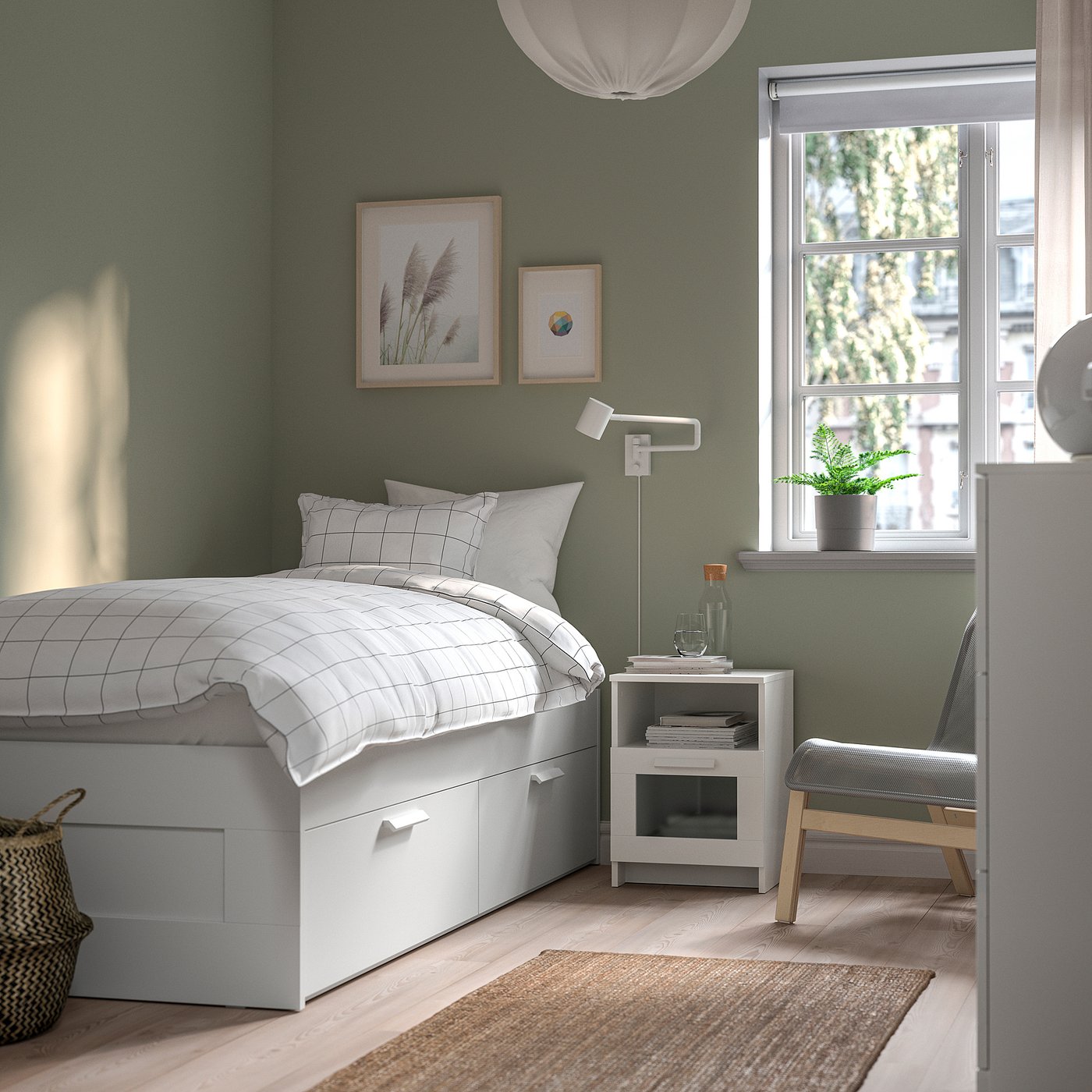 Modern green bedroom with white bed, grey chair, and minimalist decor.