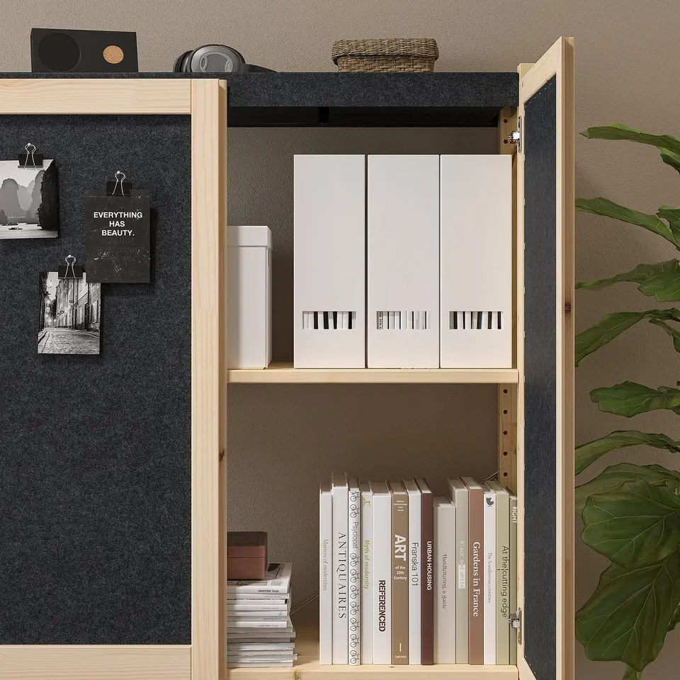 Wooden cabinet with black felt lining, adjustable shelves holding books and boxes, open door revealing organised contents.