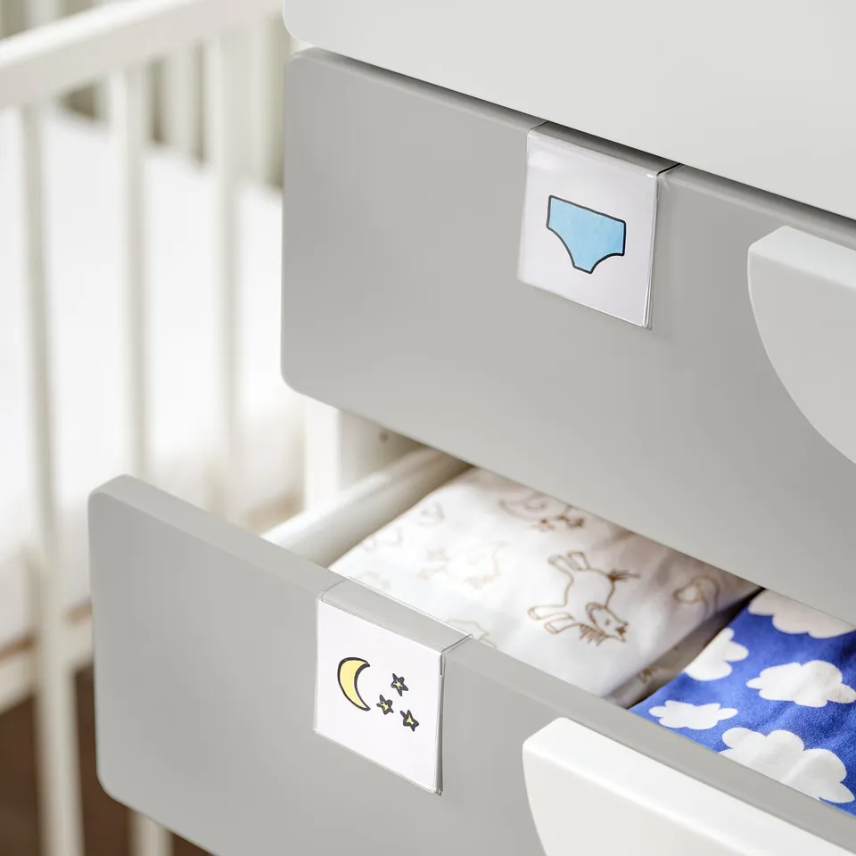 White HÄNGIG label holder with blue and star stickers, organising drawer labels.