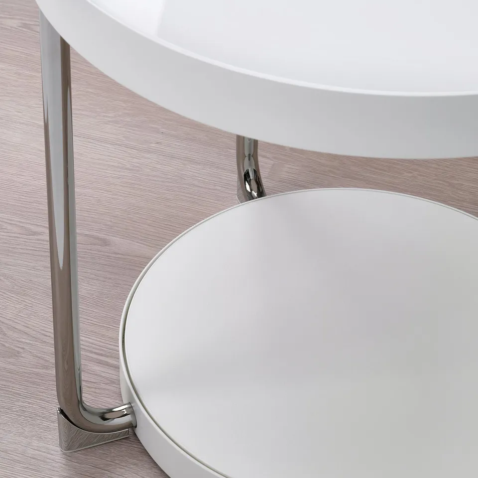 Round white table with glass top and chrome legs, displaying sleek modern design.