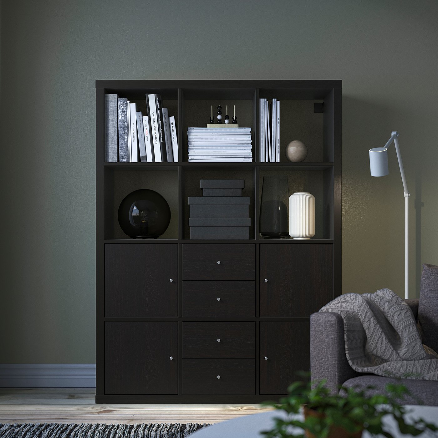 KALLAX black bookshelf with books & decor against green wall. Tall, rectangular, with storage.