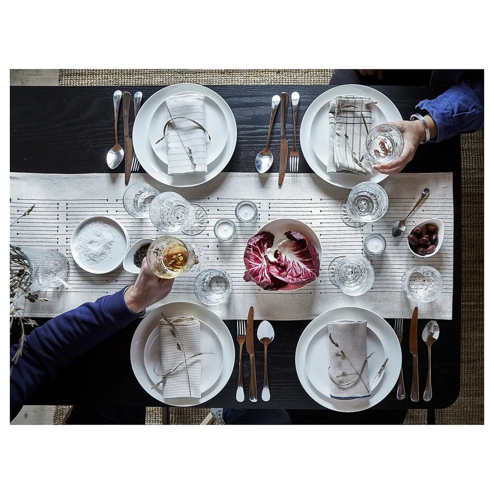 Four people having dinner at a rustic table with VÅRARV table runner.