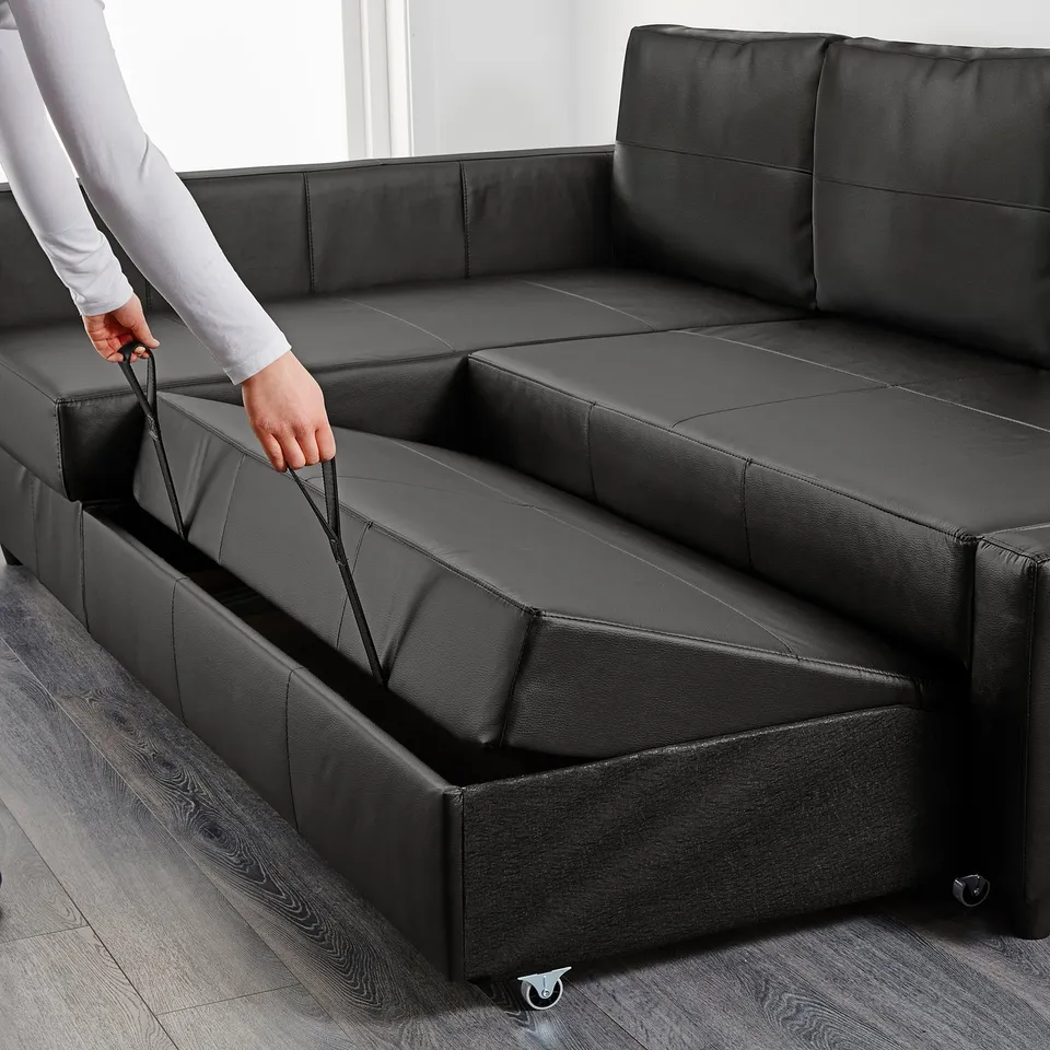 Person pulling out bed mechanism from black convertible sofa.