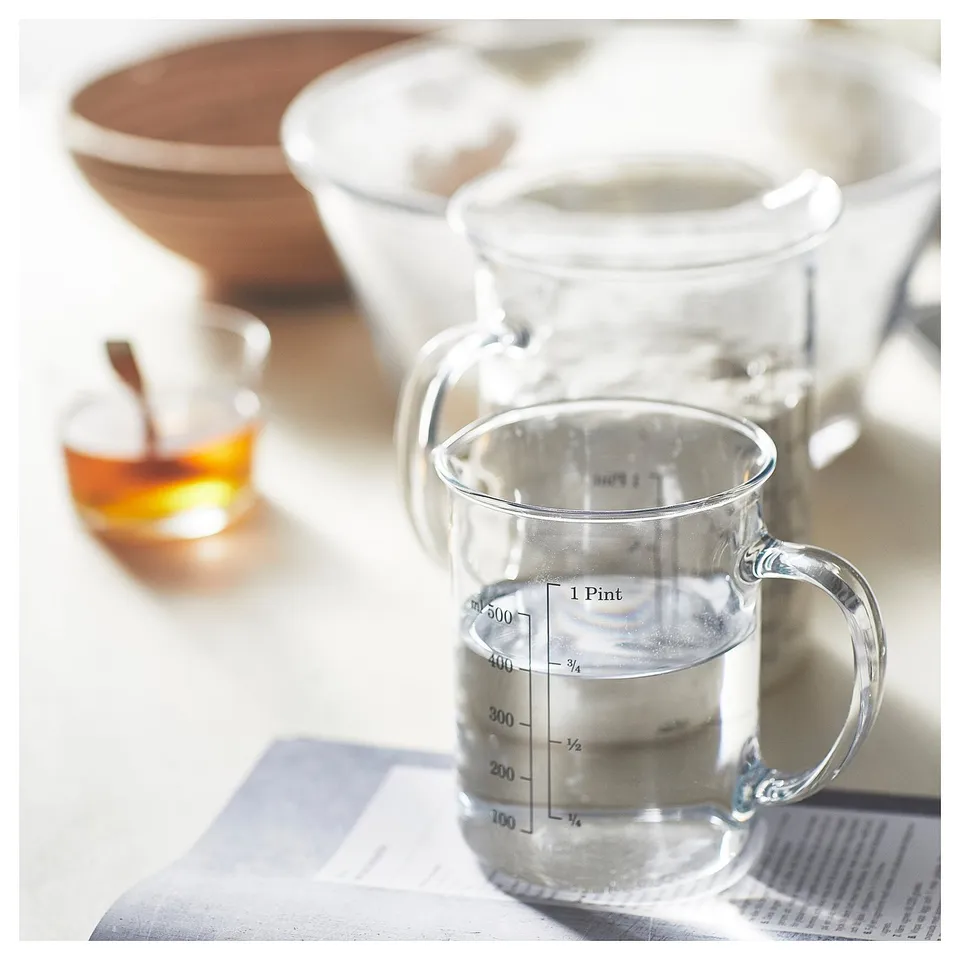 Clear glass measuring jug with handle and volume markings. Kitchen tool for liquids.
