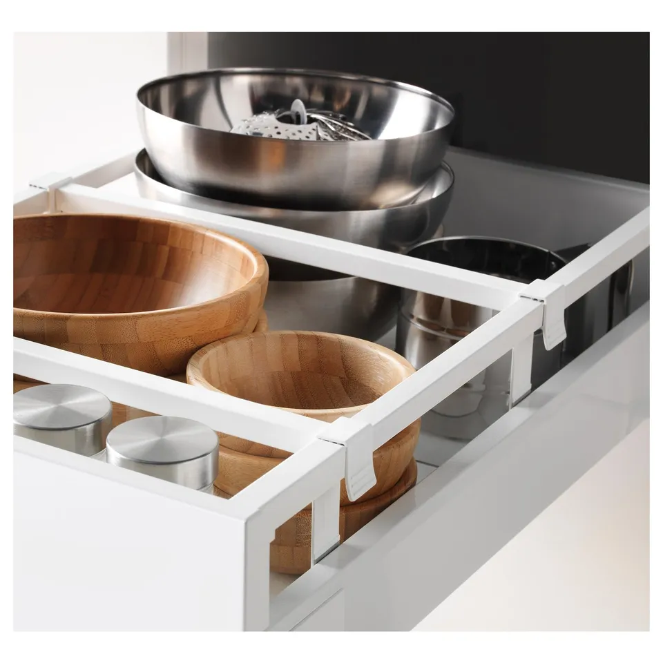 White kitchen cabinet with adjustable shelf holding wooden and metallic bowls, demonstrating storage and organisation capability.