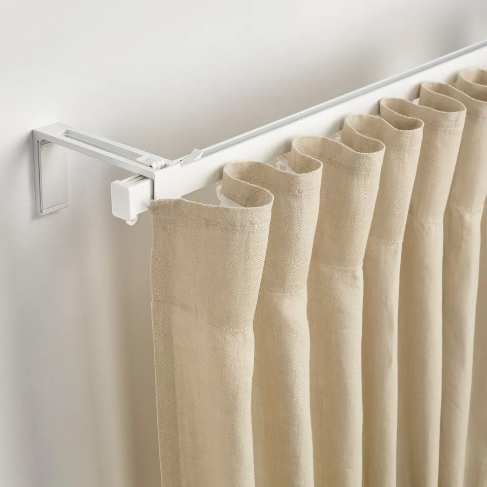 Curtain rail with beige fabric, featuring a white wall fitting and gliders.