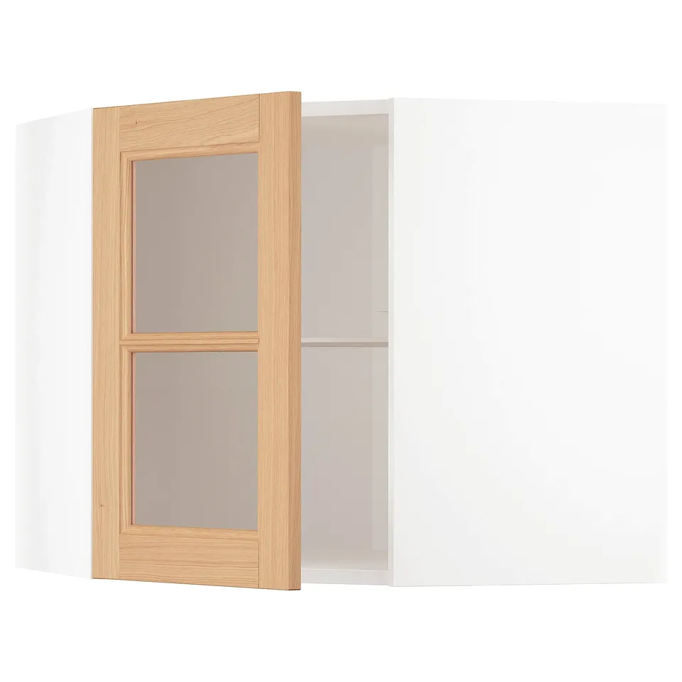 A METOD kitchen cabinet with oak-framed glass doors. The cabinet is a light wood tone with clear glass doors, designed to fit into corners.