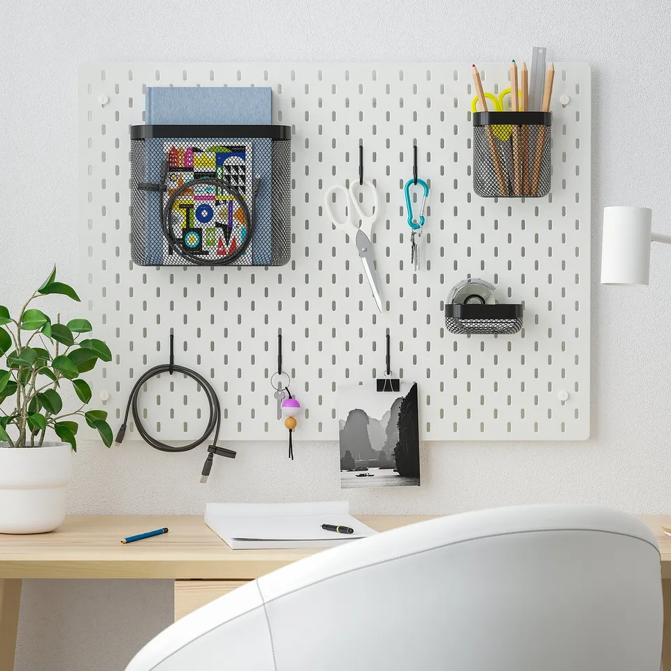 SKÅDIS pegboard with accessories on wooden desk and white chair.