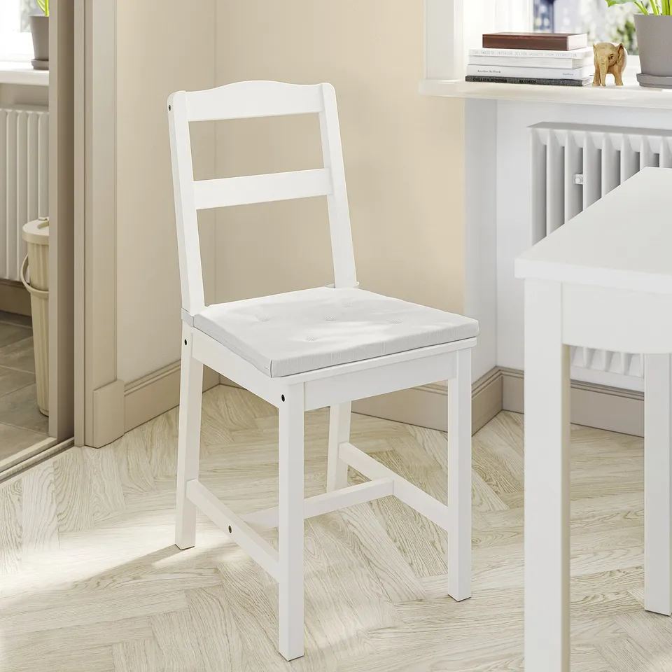 White JUSTINA chair with cushioned seat in dining room.