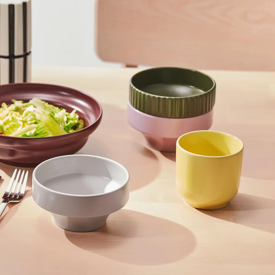 Four colourful bowls on a table, one with salad, suitable for serving various foods and creating lively table settings.